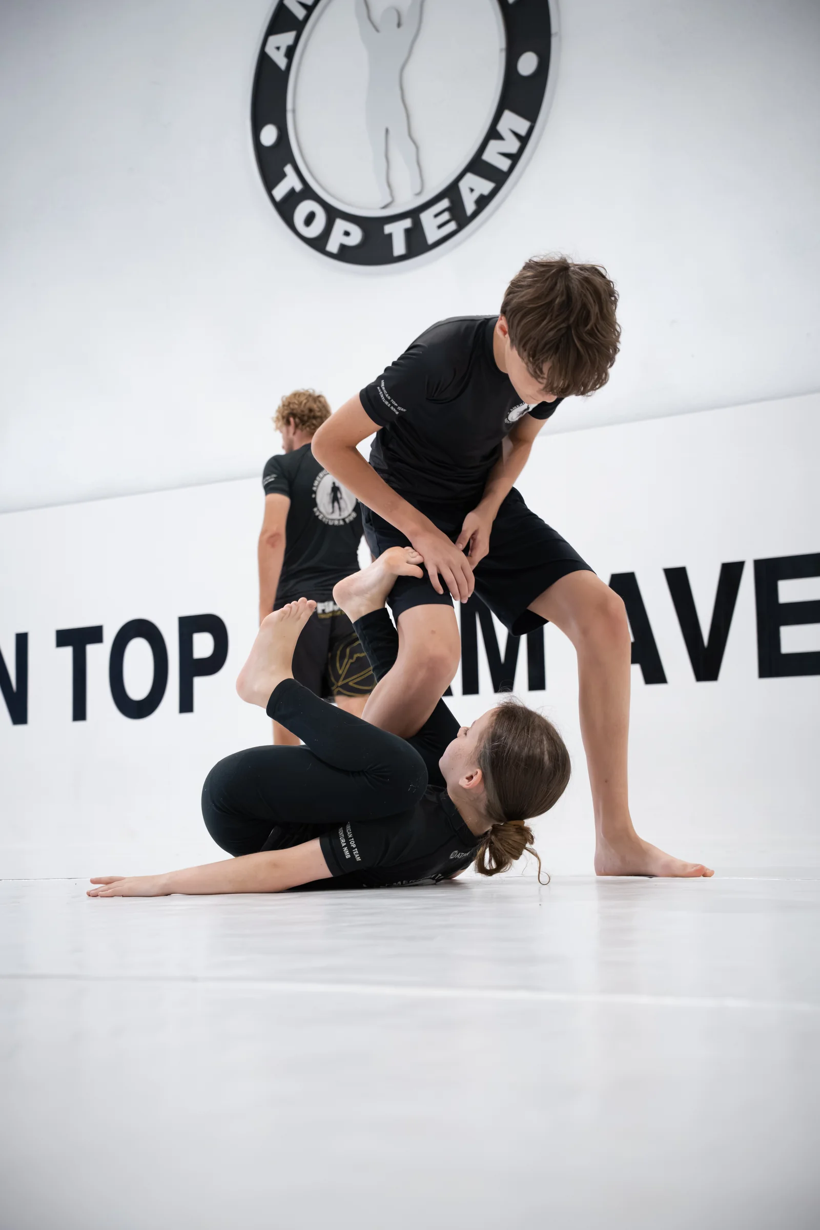 Young training partners practicing Brazilian Jiu-Jitsu on the academy mats